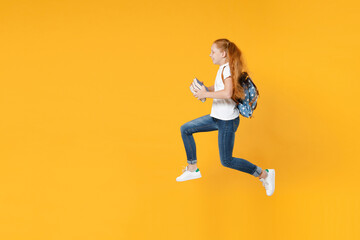 Fototapeta na wymiar Full length jumping up fun redhead teen kid girl 12-13 years old in white t-shirt backpack hold school textbook book isolated on yellow background children studio portrait Education lifestyle concept