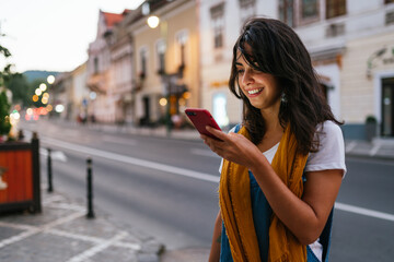 happy woman on the street reading a text that makes her smile