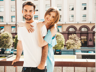 Portrait of smiling beautiful woman and her handsome boyfriend. Woman in casual summer jeans dress. Happy cheerful family. Female having fun. Couple posing on the street background