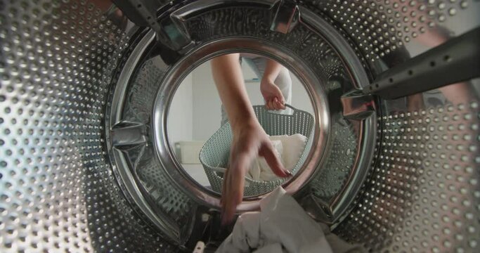 A woman pulls clean washed white linen from the washing machine