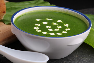 spinach cream soup in a bowl with fresh bread and cream