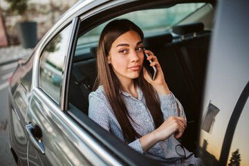 Fototapeta na wymiar Businesswoman with mobile phone in back seat of car