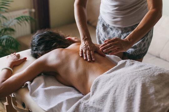 Masseur doing massage of female back indoor