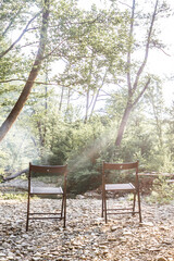 Camping at beach of mountain river. Two chairs in the forest. Summer travel theme.