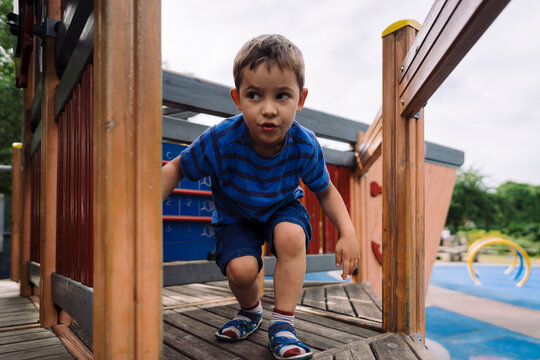 Little boy going bending down on playground platform