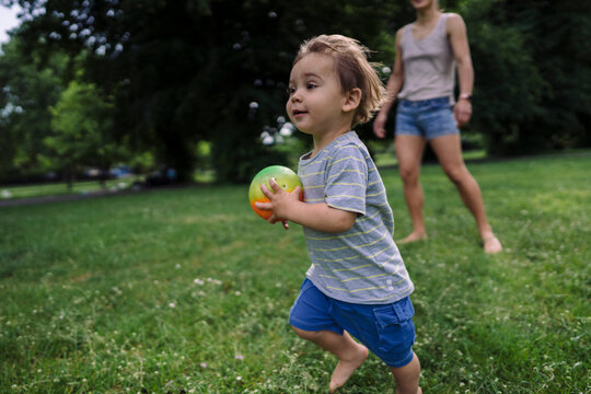 Little boy running with ball on grass