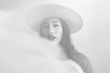 Black and White Portrait of Mixed Race Asian Female in Hat Through Sheer Sheet