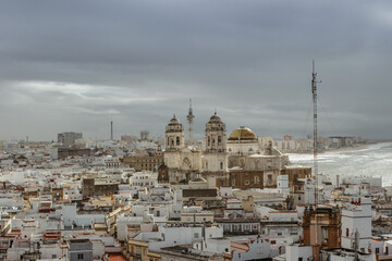 Fototapeta na wymiar Aerial dramatic panoramic view of the old city, rooftops and Cathedral de Santa Cruz in cloudy day from tower Tavira in Cadiz, Andalusia, Spain.European cityscape.Beautiful white city by sea
