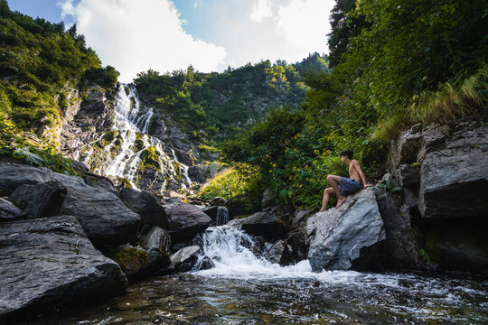 Young boy ready to jump on the water from a waterfall.