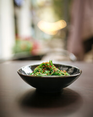 Green chuka seaweed salad in a black bowl