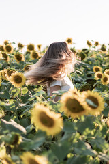 Young beautiful woman smiling and having fun in a sunflower field on a beautiful summer day.