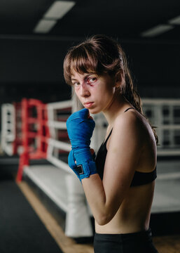 young attractive girl is engaged in boxing. dark boxing gym with a ring