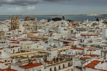 Fototapeta premium Aerial dramatic panoramic view of the old city, rooftops and seashore in cloudy day from tower Tavira in Cádiz, Andalusia, Spain.European cityscape.Beautiful white city on the the Atlantic coast
