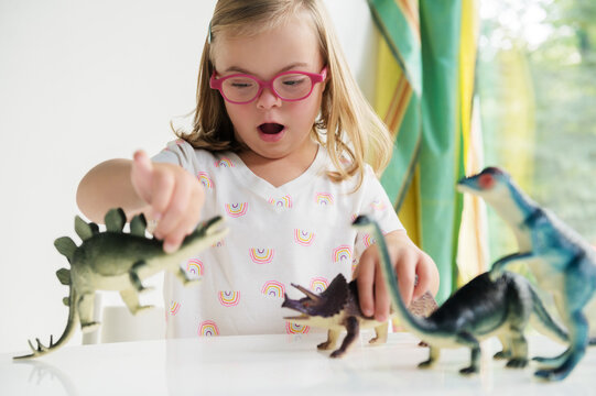 Little girl with down syndrome playing with dinosaurs