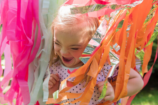 Joyful girl with down syndrome running through streamers