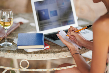 Student taking notes from laptop outside