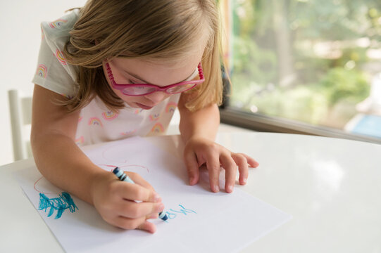 Little Girl With Down Syndrome Writing Name With Crayon