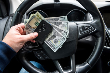 Car key and dollar in hand inside auto