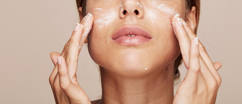 Woman portrait applying cream or moisturiser isolated
