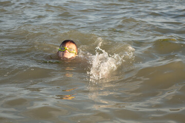 A handsome boy of 10 years old swims in the sea in different styles - on the back, breaststroke, crawl.