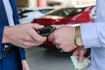 Obraz na płótnie Canvas Male hand with car keys against new car in showroom