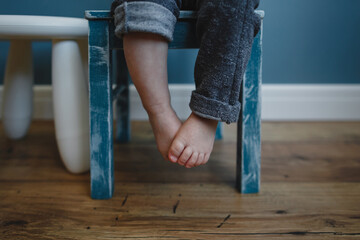 Cute little baby feet sitting on a blue chair