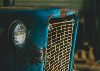 Rusted front end of an old vintage blue tractor 