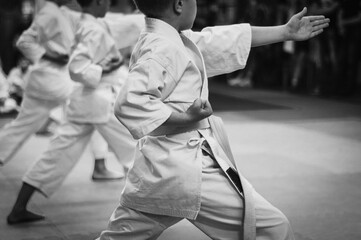 Kids training on karate-do.  Black and white. Photo without faces.Simulating the grain of film photography. © Uladzimir