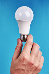 idea concept. caucasian male businessman holding white led bulb over blue background