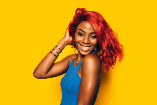 Happy Black Woman posing over yellow background with red wig