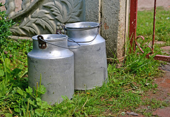 Obraz premium Aluminum bidons for milk stand against the background of a fence in the courtyard