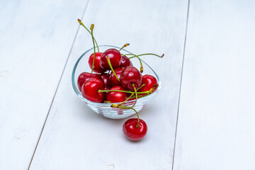 Obraz na płótnie Canvas ripe cherries in a glass bowl on a white wooden table