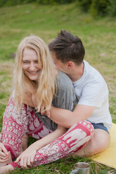husband hugs a smiling wife. sit together on a karemat