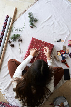 Anonymus woman tie cordon on gift.