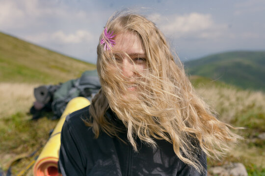 blonde girl looking at the camera and burning. hair covered the face. a flower in the hair
