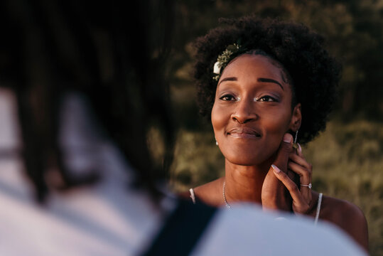 A beautiful young black bride and groom posing for portraits in a meadow on their wedding day - Powered by Adobe