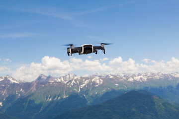 Fototapeta na wymiar Drone in the air against a mountain landscape. Modern copter in a mountainous area. Aircraft with a professional camera in the air