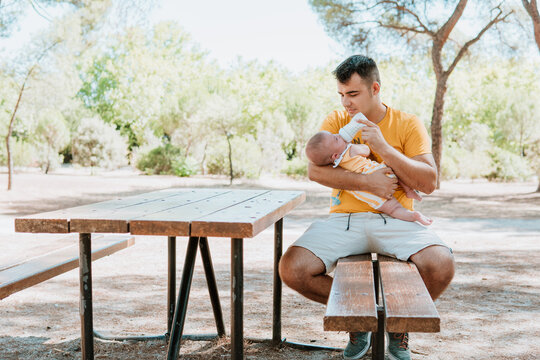 Father feeding baby on park bench