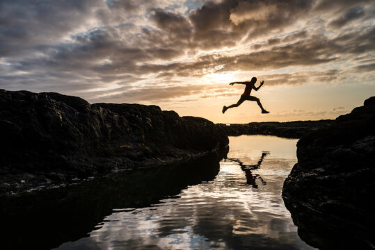 Strong active man exercising by rocky shore on cloudy day - Powered by Adobe