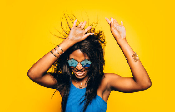 Happy Afro Woman posing over yellow background moving her hair
