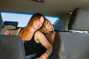 Smiling female friends having fun, singing and dancing inside auto salon during road trip, crazy friendship and adventures.