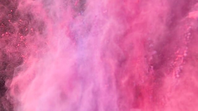 Super slow motion explosion of colorful multicolored powder on dark isolated background. Lumps of powder fly upwards and mix with the smoke.