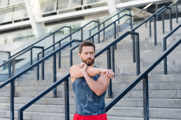 Preparing his muscles. Fitness man warming up in the gym. Having a good stretch. Handsome man in sports clothing stretching while warming up outdoors. Great warm-up. Sporty handsome