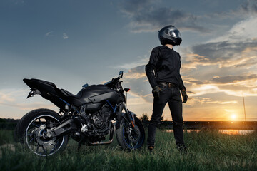 Biker and motorcycle in sunset on the country road.