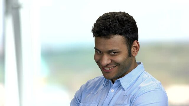 Smiling macho man showing silence gesture. Young handsome Indian man with finger on lips. Man with seductive look on blurred background.