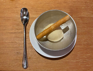 a scoop of vanilla ice cream served in a cup with a wafer roll