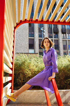 girl in a purple dress sits on a red metal construction