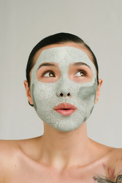 Closeup portrait of a charming Asian girl with a clay mask on her face and interesting emotion