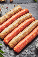 Raw butchers sausages on slate with herbs. Overhead view