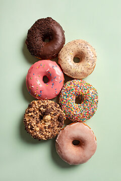 Bright iced glazed donuts on green background